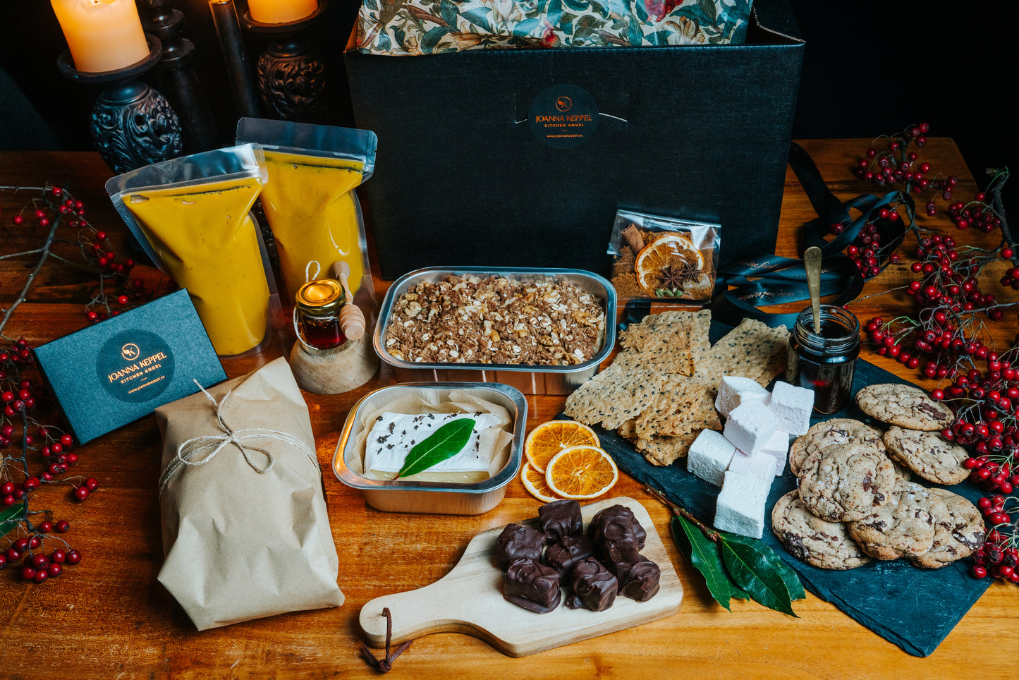 Gourmet food platter with various items including cookies, nuts, pumpkin soup, brie, and a cutting board on a wooden table.