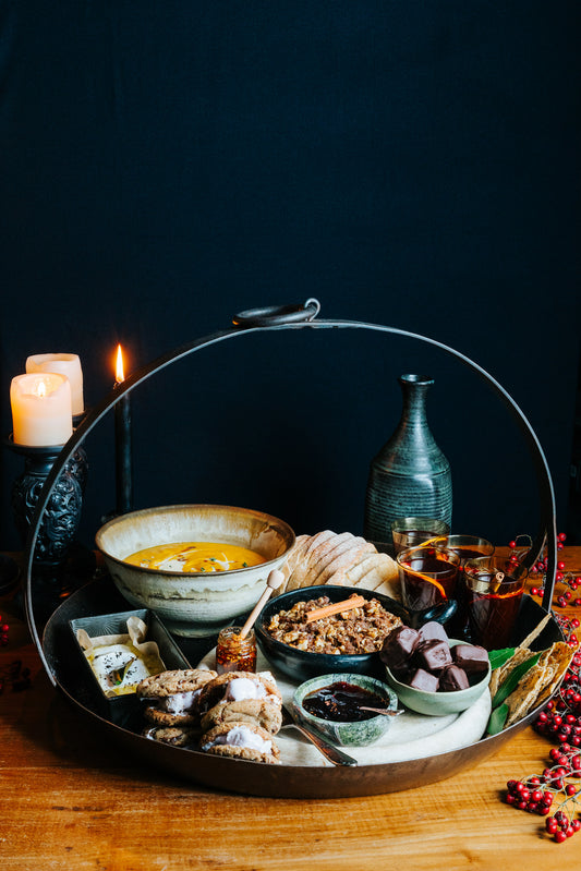 Platter with contents of Queenstown Winter Warmer Gift Hamper, including pumpkin soup, baked brie, apple crumble, s'mores, chocolates, mulled wine and more!